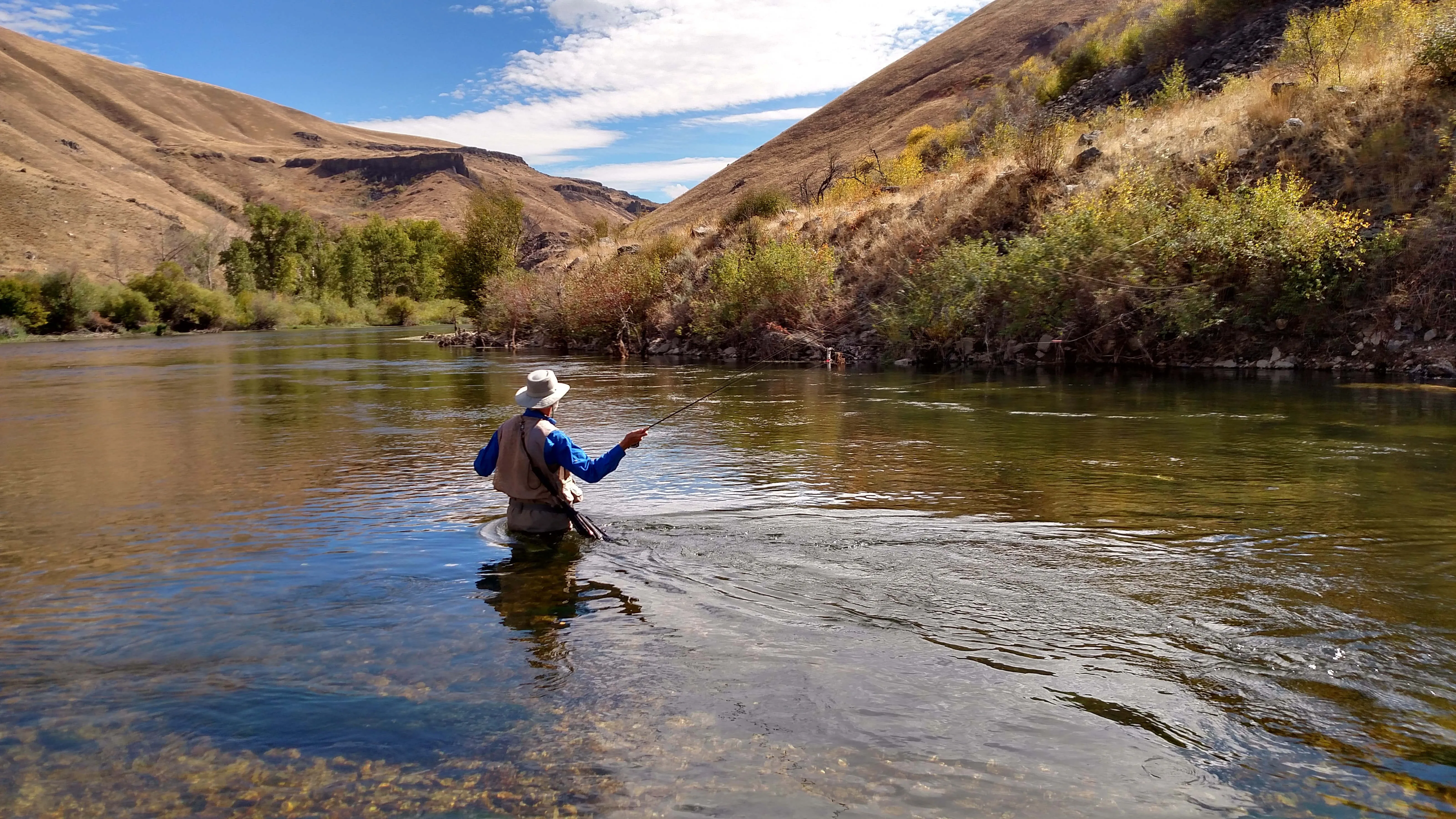 Angler casting a fly line on a canyon river